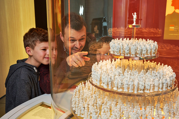 Vater und zwei Kinder vor einer Vitrine mit Römerfiguren auf einer Etage im Museum und Park Kalkriese